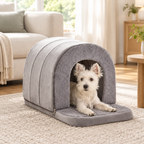 Small white dog lying at the entrance of the grey cave pet house